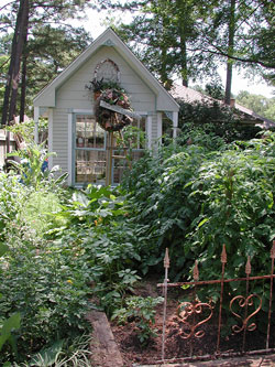 A small “herb shed” becomes a charming focal point in this lush summer garden.