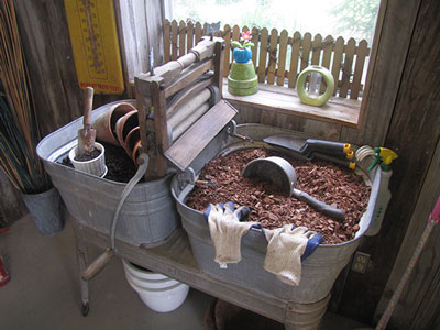 Beneath a large window that was added for light in the carport, an old double-tub wringer washer takes on new life as a potting station.